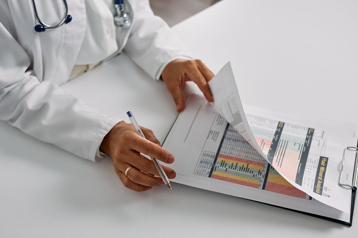 Médico conferindo formulário clínico em prancheta (foto de banco de imagens — demonstração temporária, ver CREDITS.md)